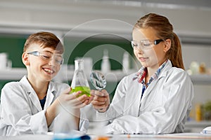 Kids with flask and magnifier at chemistry class