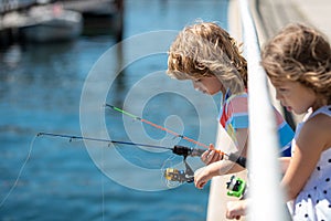 Kids friends fishing on weekend. Two young cute kids fishing on a lake in a sunny summer day. Friendship.