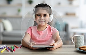 Kids And Gadgets. Cute Preteen Girl In Wireless Headphones Using Digital Tablet