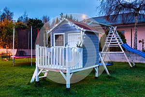 Kids garden house illuminated at night by christmas lights