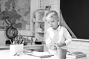 Kids gets ready for school. School interiors.Happy cute industrious child is sitting at a desk indoors.