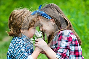 Kids girl and boy blowing dandelion flower in green meadow outdoor.