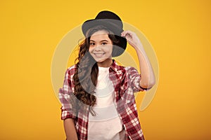 Kids girl in old fashion clothes. Elegent hat, cylinder hat isolated on yellow background. Headwear. Clothes accessories photo