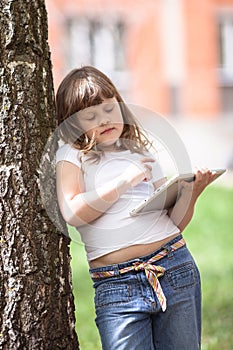 Kids girl playing with tablet on stump, childhood