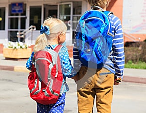 Kids go to school- little boy and girl with backpacks on street