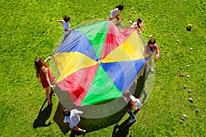 Kids going round in a circle with bright parachute