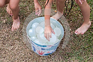 Kids grabbing water balloons from metal bucket