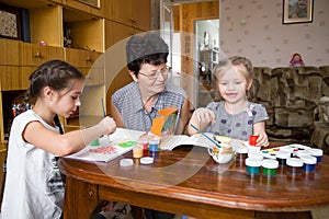 Kids and grandmother painting at home