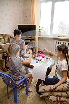 Kids and grandmother painting at home, vertical