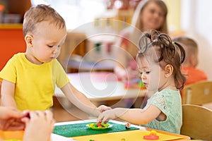 Kids group making arts and crafts in kindergarten. Children on lesson in daycare centre