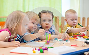 Kids group making arts and crafts in kindergarten. Children spending time in day care centre with the great interest.