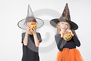 Kids Halloween. A beautiful cute girl in a witch costume and a boy holding baskets in the shape of Jack's lantern.