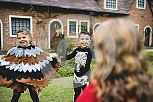 Kids in Halloween costumes holding hands in a park