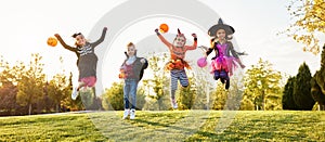 Kids in Halloween costumes jumping on lawn