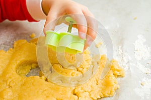 Kids hand with form of christmas cookies for children, making gingerbread in form of man. New year treat for Santa Claus cooking.