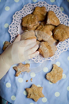 Kids hand take healthy homemade cookies from a pink plate