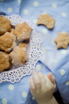 Kids hand take healthy homemade cookies from a pink plate