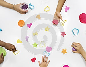 Kids hands with colorful clays on white table