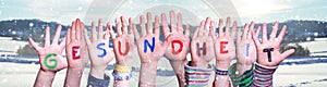 Kids Hands Holding Word Gesundheit Means Health, Snowy Winter Background photo