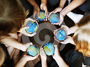 Kids hands holding cupping globe balls together