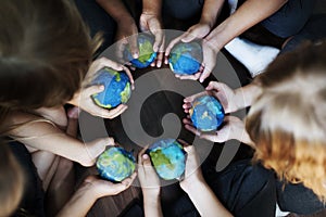 Kids hands holding cupping globe balls together photo