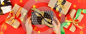 Kids hands holding decorativegift box with bow on red background. Sale, Holiday, greering card Happy new year 2022, Merry