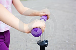 Kids hands holding handlebar scooter