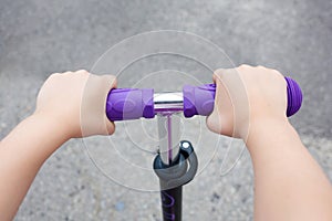 Kids hands holding handlebar on scooter photo