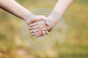 Kids` hands holding for support and friendship, outdoor with blu