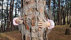 Kids hands hugging tree trunk