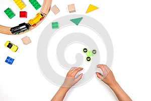 Kids hands playing with fidget spinner toy. Many colorful toys on white background.