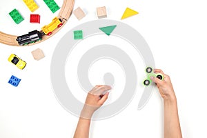 Kids hands playing with fidget spinner toy. Many colorful toys on white background.