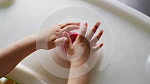 Kids hands playing slime toy in home. Little girl is playing with a homemade pink slime.