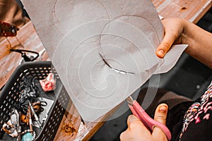 Kids hands with scissors cutting out a circle, miniature items on the table,kids crafting diy