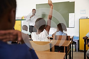 Kids with hands up in elementary school class, low angle