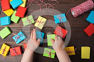 Kids hands which put or give colorful gift boxes on table