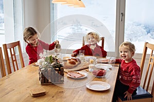 Kids having breakfast on Christmas morning. Family eating bread and drinking milk at home on snowy winter day. Children eat in