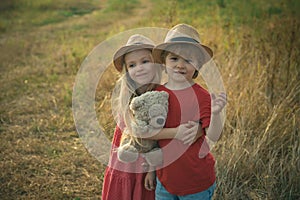 Kids having fun in field against nature background. Happy children girl and boy hug on meadow in summer in nature