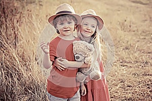 Kids having fun in field against nature background. Happy children girl and boy hug on meadow in summer in nature
