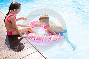 Kids having fun playing in swimming pool on summer vacation