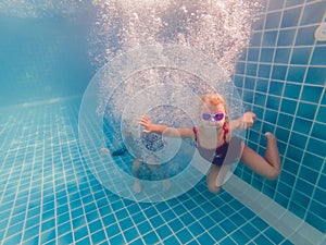 Kids having fun playing underwater in swimming pool on summer vacation