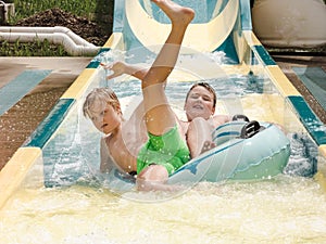 Kids having fun riding water slides on summer vacation