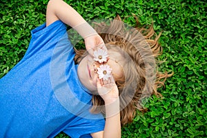 Kids having fun in spring park. Child lying on green grass. Top view portrait.