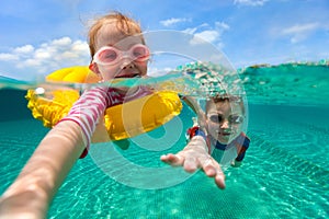 Split sopra e sott'acqua foto di adorabili figli divertirsi nuoto in vacanza d'estate.