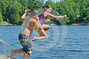 Kids having summer fun jumping off dock into lake