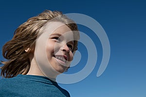 Kids head on blue sky with copy space, close up. Close up head shot of child. Kids looking away, little boy face