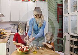 Kids helping mother preparing vegetable salad.