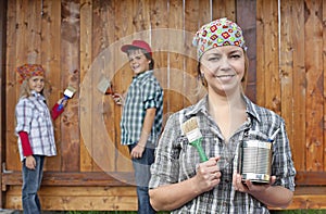 Kids helping their mother painting the wood shed