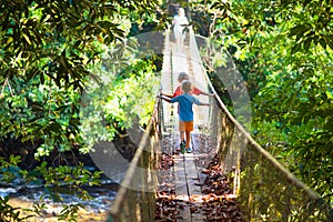 Kids hiking in the mountains. Bridge over river