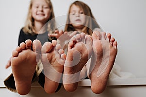 Kids hold feet close up to the camera. Their blurred faces in a background.